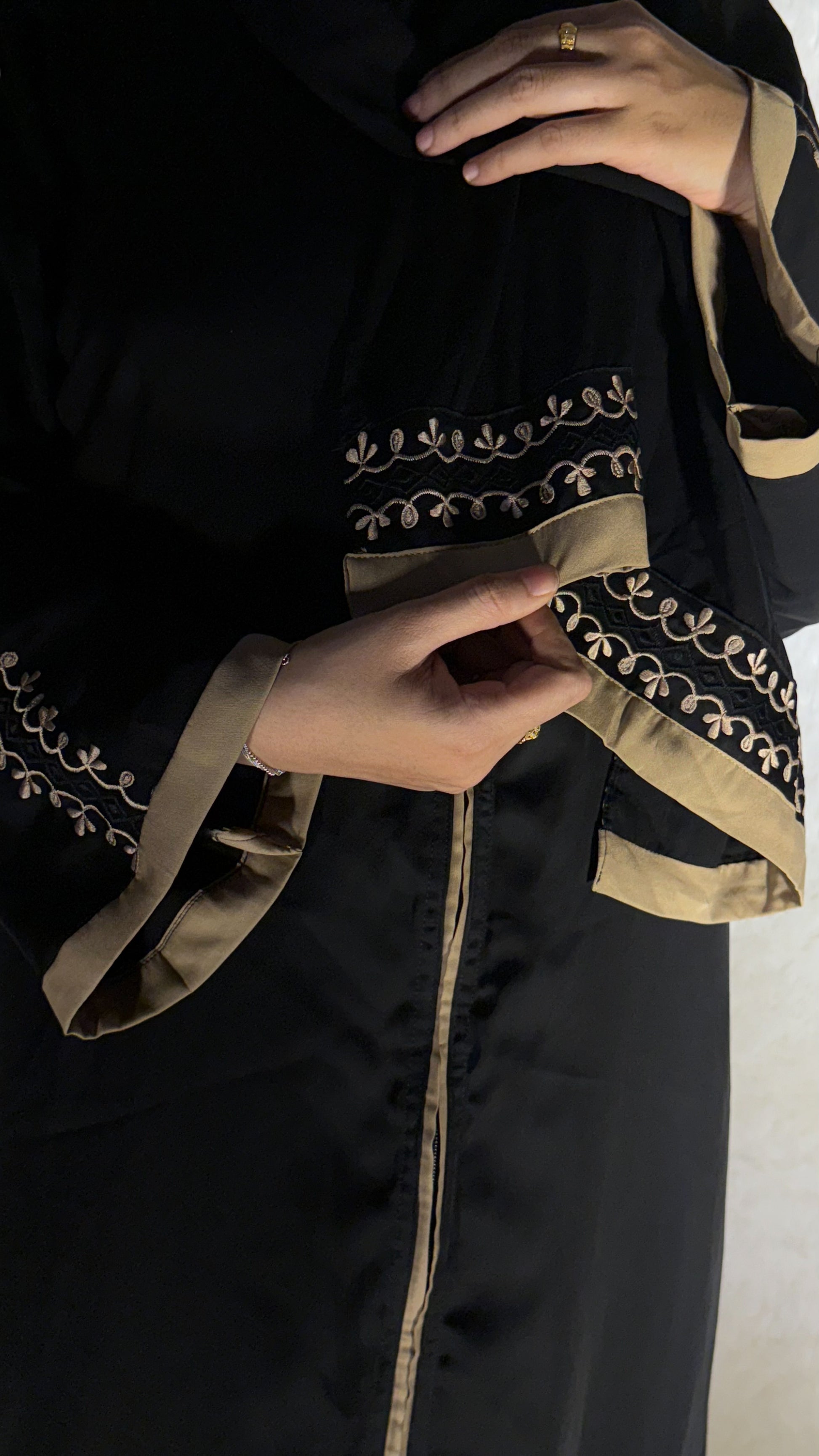Black garment with gold embroidery and trim on a neutral background