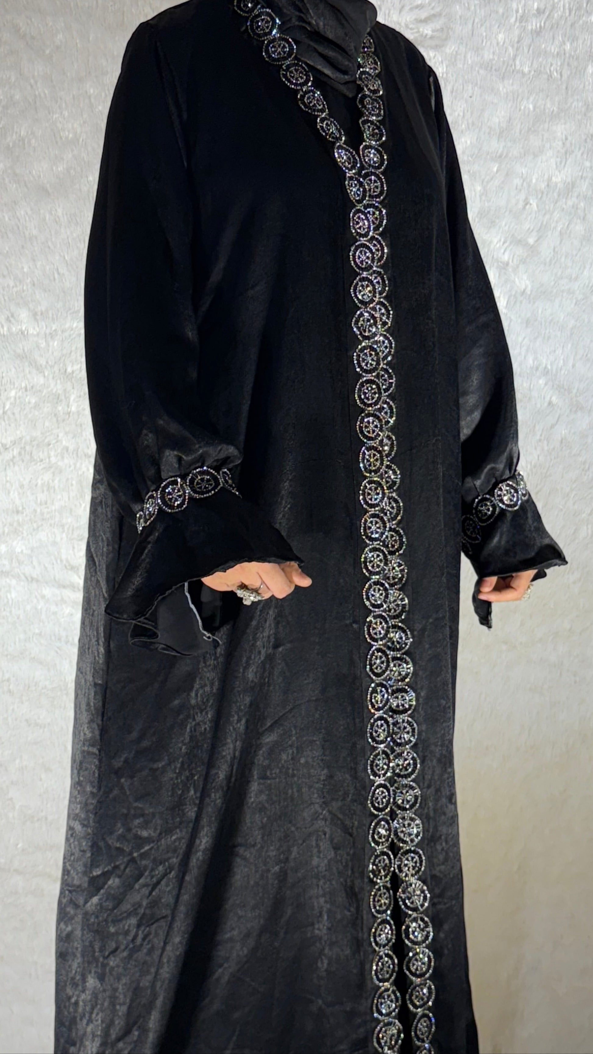 Black abaya with intricate white embroidery on a plain background